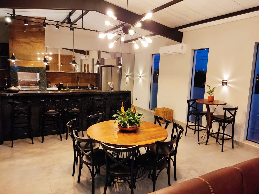 Sala de jantar de um cliente da Toth com mesa redonda de madeira, seis cadeiras pretas de encosto em X, balcão com banquetas ao fundo e mesa alta de bistrô ao lado