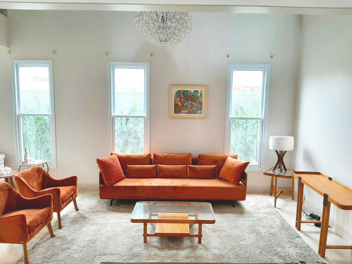 Sala de estar com sofá e poltronas em tecido terracota no showroom da Toth