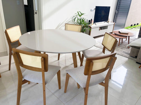 Sala de jantar integrada de um cliente, com mesa redonda de tampo branco e cadeiras de madeira com encosto de palhinha em volta